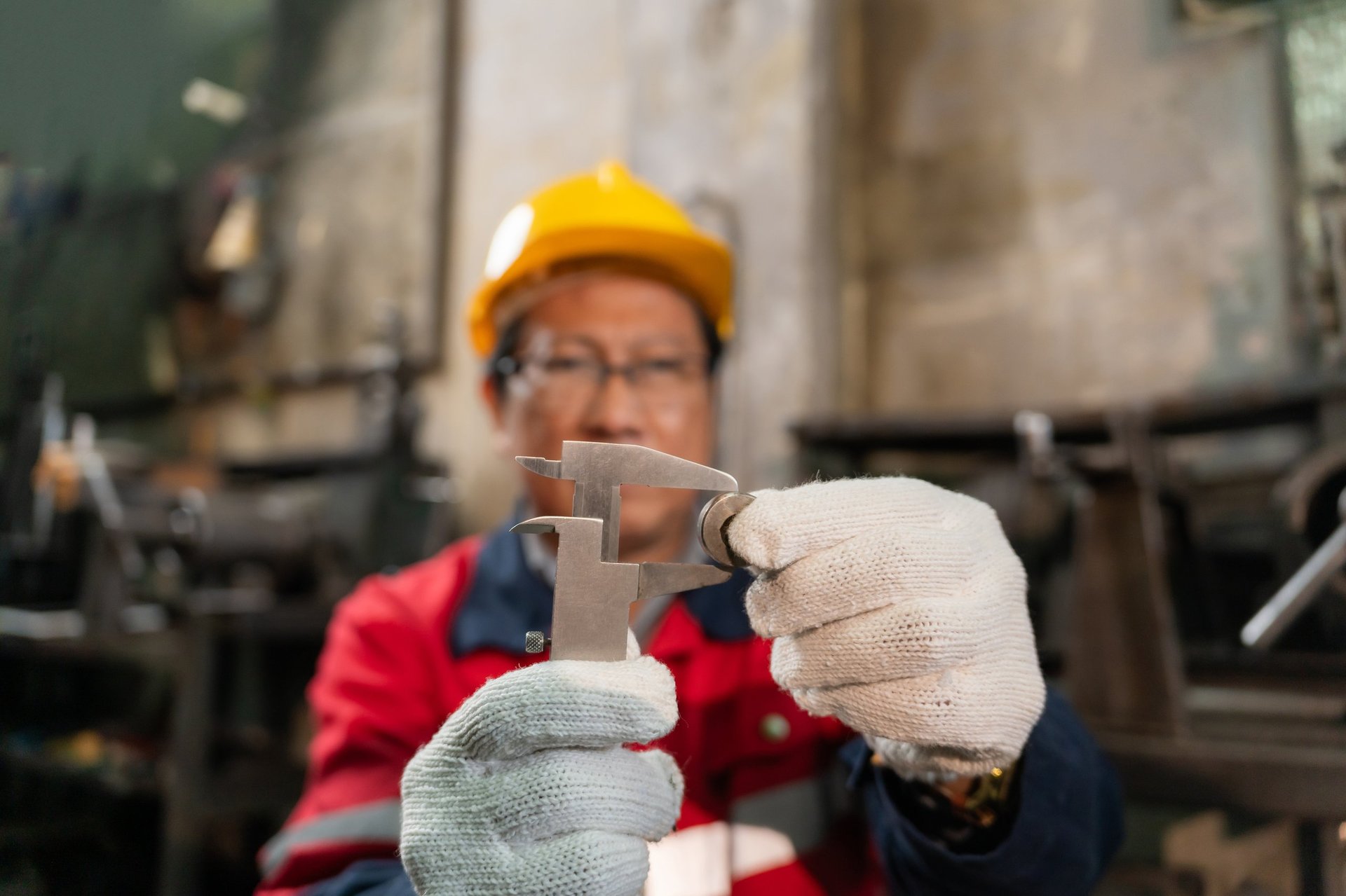 Technician using a vernier caliper to measure a machined component in an industrial workshop