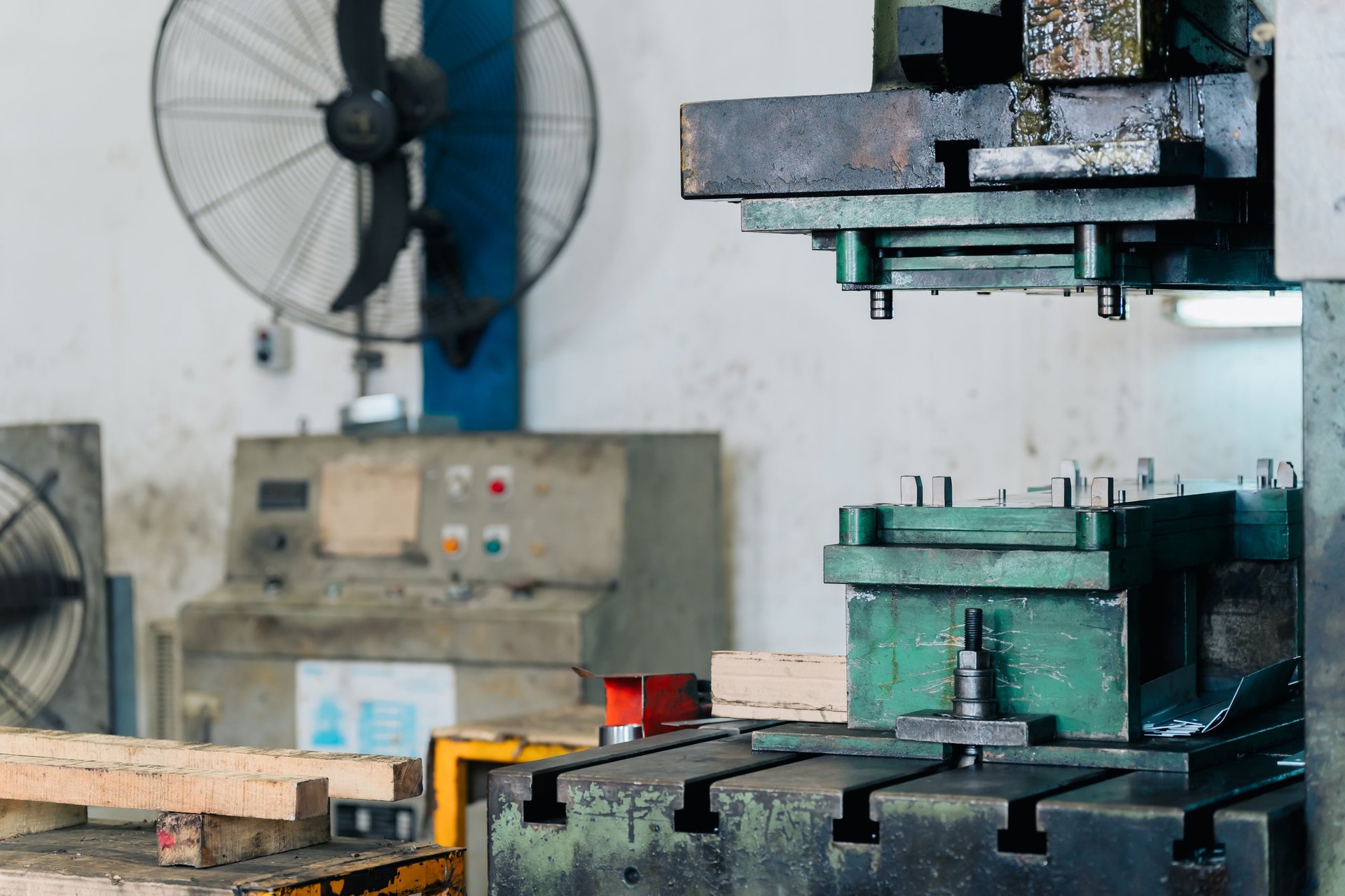 Operators working a hydraulic press on a metalworking production floor