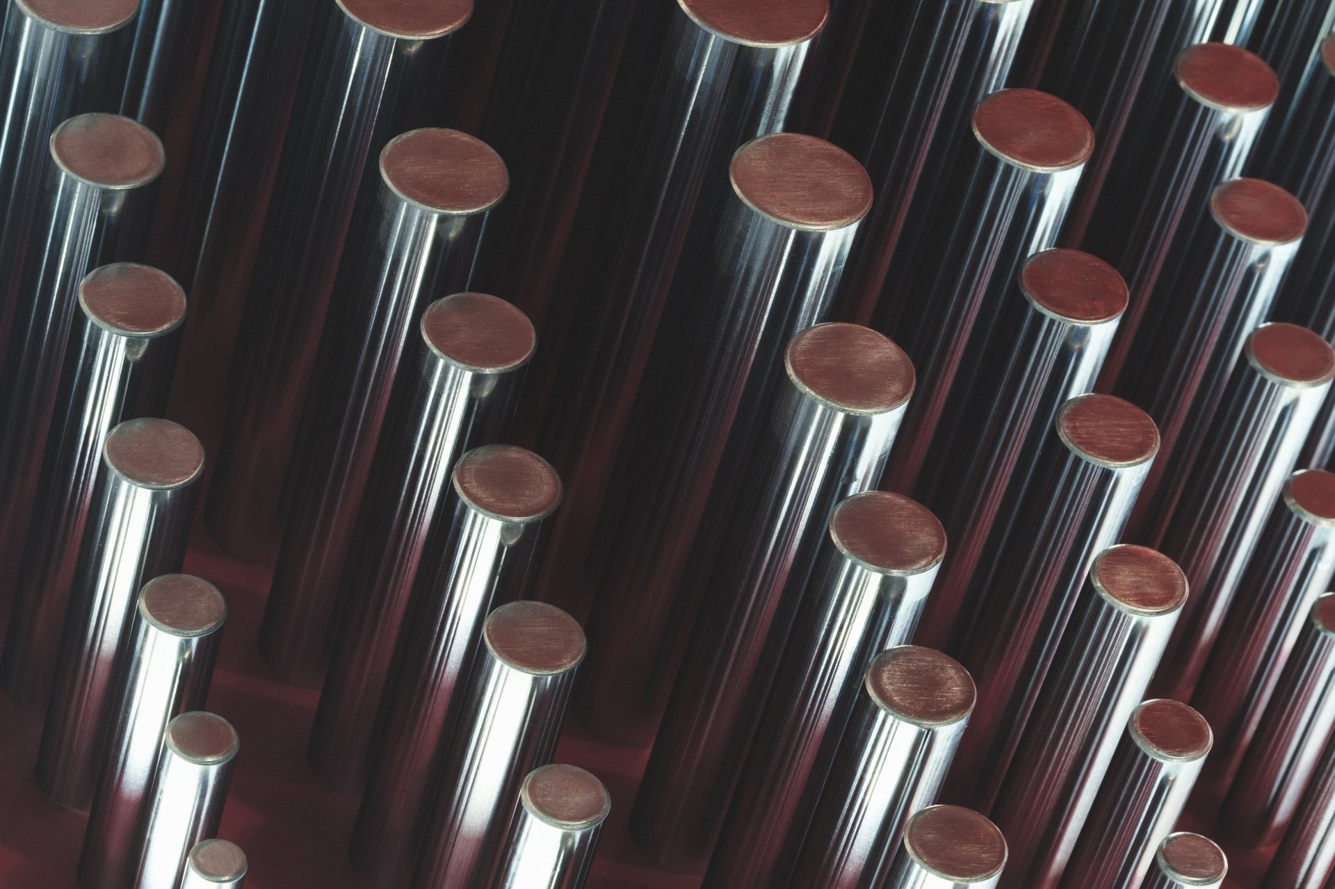Smooth plain metal round bars stacked in even rows, showing the unribbed surface