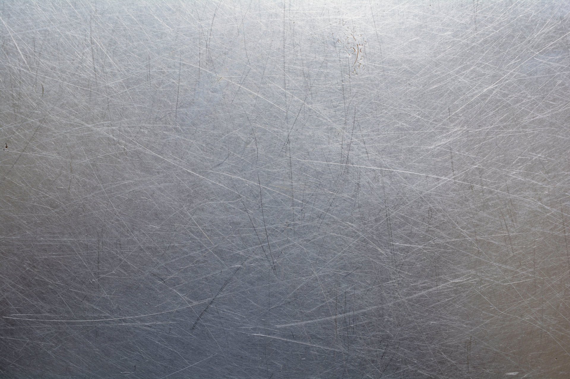 Close view of a bare rolled metal surface showing the fine directional texture a zinc coating is applied over