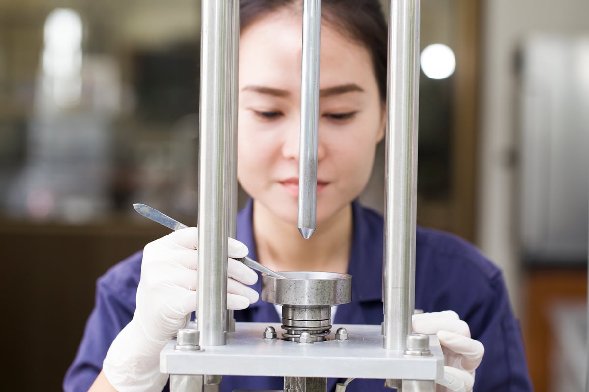 Engineer setting up a mechanical testing machine for a steel specimen, illustrating the per-heat mechanical evidence a high-strength grade assessment depends on.